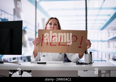 Upset Doctor Woman Holding Cardboard With Help Text In Office Stock Photo