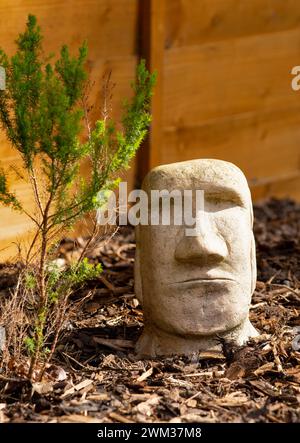 Christmas Island style stone garden statue on bark in garden on sunny day Stock Photo