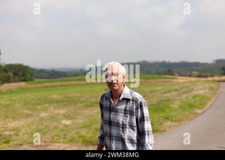 Portrait of an elderly man standing on the road in the countryside Stock Photo