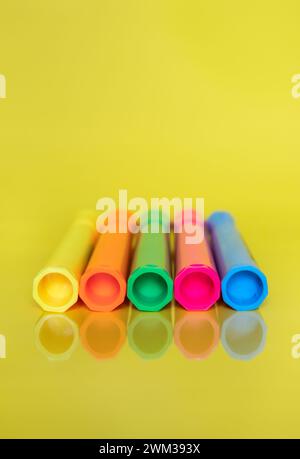 Coloured fluorescent highlighter marker pens on bright yellow background Stock Photo