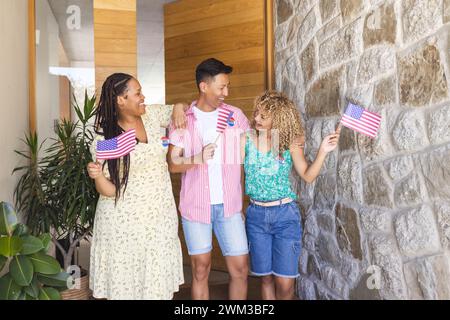 Diverse friends celebrate with American flags, wearing vote badges Stock Photo