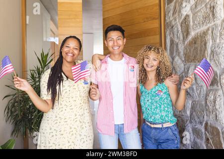 Diverse friends hold American flags and are wearing vote badges Stock Photo
