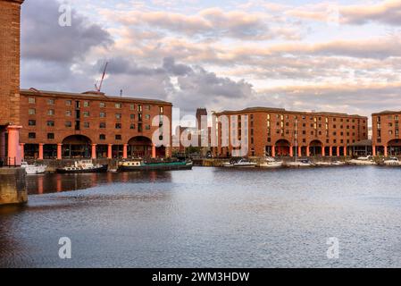 View of Royal Albert Dock with renovated brick dockside warehouses in Liverpool at sunset. Liverpool Anglican Cathedral is visible in background. Stock Photo