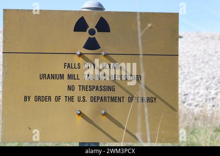 A “Uranium Mill Tailing Repository” and a “Radiation Warning” symbol on a sign along the perimeter fence at the Falls City disposal site near Karnes County, Texas, USA, on February 23, 2024. The Falls City disposal site contains 5.1 million cubic yards of contaminated material, with a total activity of 1,277 curries of radium- 226. The disposal site is located over the Eagle Ford Shale Geological Area, which is an active oil and gas producing region. Recently, the area has had 20 earthquakes of a magnitude 2.5 or or higher in a span of 30 days. (Photo by Carlos Kosienski/Sipa USA) Stock Photo