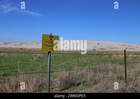 A “Uranium Mill Tailing Repository” and a “Radiation Warning” symbol on a sign along the perimeter fence at the Falls City disposal site near Karnes County, Texas, USA, on February 23, 2024. The Falls City disposal site contains 5.1 million cubic yards of contaminated material, with a total activity of 1,277 curries of radium- 226. The disposal site is located over the Eagle Ford Shale Geological Area, which is an active oil and gas producing region. Recently, the area has had 20 earthquakes of a magnitude 2.5 or or higher in a span of 30 days. (Photo by Carlos Kosienski/Sipa USA) Stock Photo