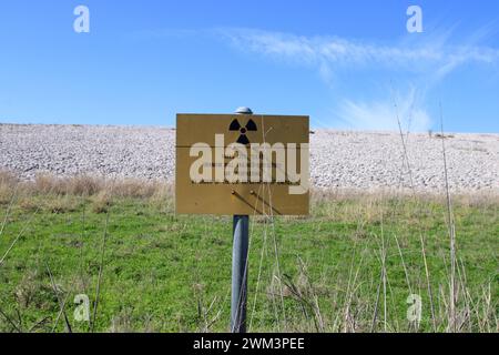 A “Uranium Mill Tailing Repository” and a “Radiation Warning” symbol on a sign along the perimeter fence at the Falls City disposal site near Karnes County, Texas, USA, on February 23, 2024. The Falls City disposal site contains 5.1 million cubic yards of contaminated material, with a total activity of 1,277 curries of radium- 226. The disposal site is located over the Eagle Ford Shale Geological Area, which is an active oil and gas producing region. Recently, the area has had 20 earthquakes of a magnitude 2.5 or or higher in a span of 30 days. (Photo by Carlos Kosienski/Sipa USA) Stock Photo