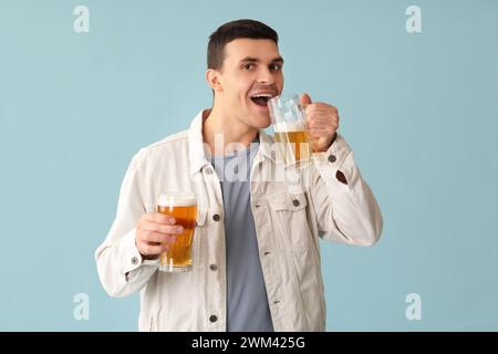 Handsome young happy man with glasses of beer on blue background Stock Photo