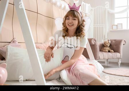 Tooth Fairy putting coins under pillow in children's bedroom Stock Photo