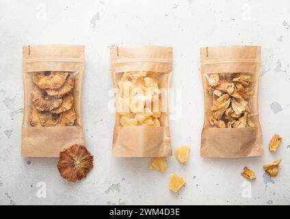 Packages with dried sweet pineapple slices and chips on light background. Stock Photo