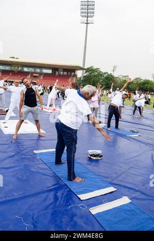 New Delhi, India, June 21, 2023 - Group Yoga exercise session for people at Yamuna Sports Complex in Delhi on International Yoga Day, Big group of adu Stock Photo