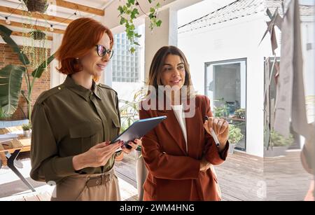 Two busy business women talking planning project with sticky notes working in office. Stock Photo