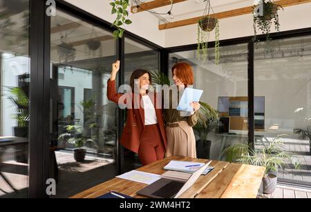 Two happy business women celebrating work success giving high five in ...