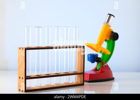 Empty chemical test tubes on a stand and a children's microscope. Chemistry lessons at school. Stock Photo