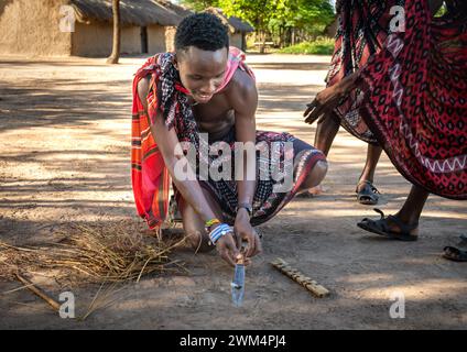 A Maasai warrior starts fire by friction after rubbing sticks together  in a village in Mikumi, Tanzania. Stock Photo