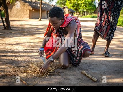 A Maasai warrior starts fire by friction after rubbing sticks together  in a village in Mikumi, Tanzania. Stock Photo