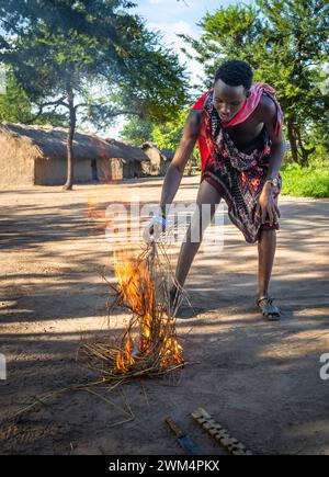 A Maasai warrior starts fire by friction after rubbing sticks together  in a village in Mikumi, Tanzania. Stock Photo