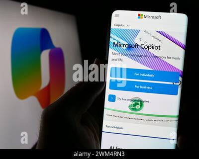 Person holding cellphone with webpage of artificial intelligence chatbot Microsoft Copilot in front of logo. Focus on center of phone display. Stock Photo