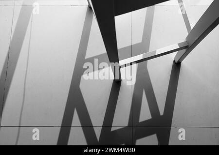 Sunlight shines through a window casting a strong shadow of a chair on the floor. Stock Photo