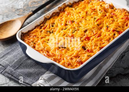 King Ranch Casserole is lined with corn tortillas, then layered with sauce and topped with cheese close-up in a baking dish on a marble table. Horizon Stock Photo