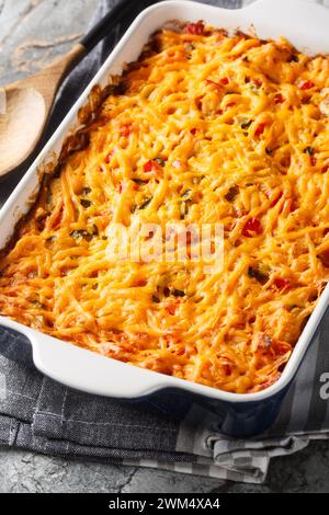 King Ranch Chicken Casserole combines juicy chicken, colorful peppers, tortillas in a bubbly creamy cheesy sauce close-up in a baking dish on a marble Stock Photo