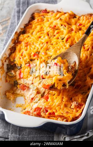 Classic King Ranch chicken casserole is bursting with chicken, corn tortillas, tomatoes, peppers, and cheesy goodness close-up in a baking dish on a m Stock Photo