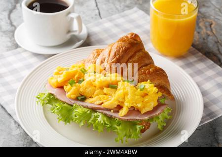 Healthy Breakfast Croissant with Scrambled Eggs and Ham Served with Orange Juice and Coffee Closeup on a Marble Table. Horizontal Stock Photo