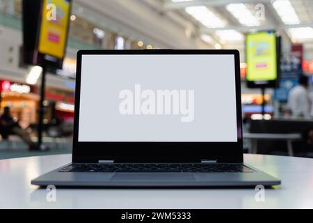 Blank white screen laptop computer on wood table with cafe restaurant abstract bokeh light defocused blur background. copy space Stock Photo