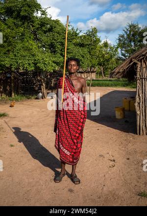 A young Maasai warrior dressed in his shuka and holding his ol-nkerr stick in his village in Mikumi, Tanzania Stock Photo