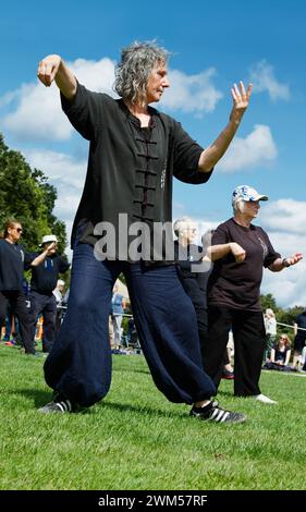 Lady In Loose Fitting Clothing Teaching Tai Chi To A Group Of The Public During A Demonstration, Exhibition, UK Stock Photo