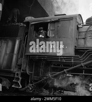 Train driver in Steam Locomotive - Chicago, Illinois. Engine taking on coal at an Illinois Central Railroad yard - Jack Delano photo 1942 Stock Photo