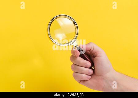 Magnifying glass in hand yellow background Stock Photo