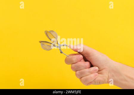 Tea strainer in hand yellow background Stock Photo