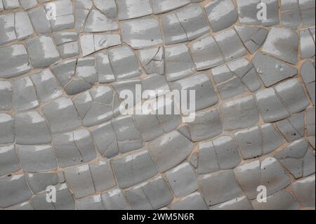 Beige and gray ceramic tile fragments forming mosaic background, sparkling in light. Radiates rustic, weathered allure, design. texture and backdrop Stock Photo
