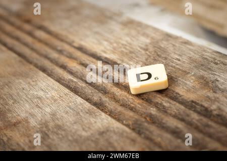 A plastic block with the alphabet d and the number 6 on it on a wooden background. Stock Photo