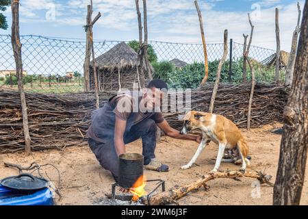 village african man and his dog in the outdoors kitchen cooking, in south africa Stock Photo