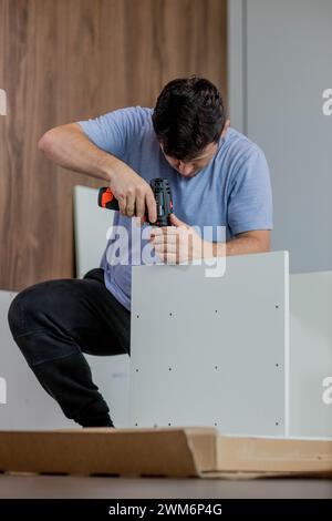 Man assembling furniture by using cordless screwdriver. Stock Photo