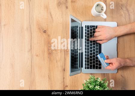 Top view of male hands making an online payment- laptop on wood background with copyspace Stock Photo
