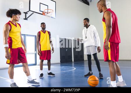 African American coach discusses strategy with basketball players in a gym, with copy space Stock Photo