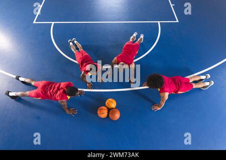 African American and biracial men doing push-ups on a basketball court Stock Photo