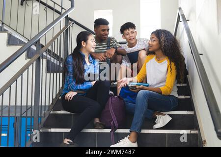 Diverse teenagers sit together on high school stairs Stock Photo