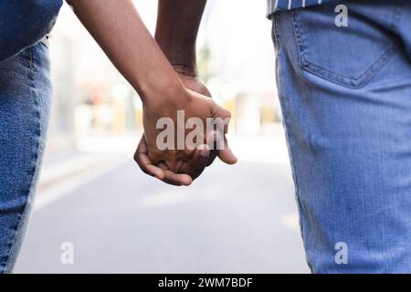 Close-up of a young African American man and a young biracial woman holding hands Stock Photo