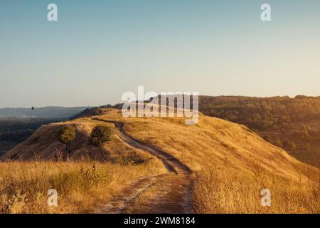 Trail on top of the hill. Unpaved winding dirt road through hilly terrain. Stock Photo
