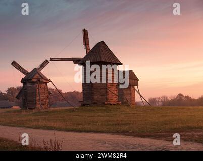 three windmills in Museum of Folk Architecture and Folkways of Ukraine in Pyrohiv. Traditional wooden windmills at sunset. Stock Photo