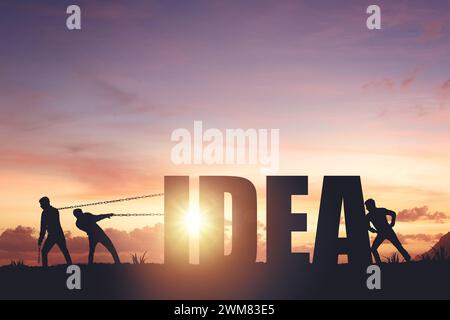 Silhouettes of people drawing the word IDEA on a sunset background, business concept Stock Photo