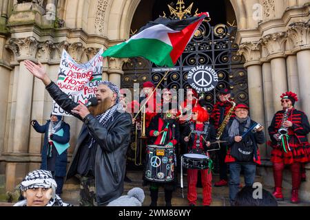Bradford, UK. 24 FEB, 2024.  Chach Hussain stands infront of the Peace artistes street band on the steps of steps of Centenary Square, Bradford. Credit Milo Chandler/Alamy Live News Stock Photo