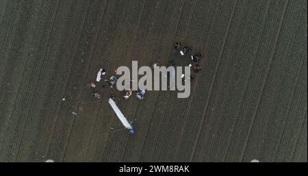 FIlm crew setting up a scene in the crop field. Hazy winter aerial drone shot. Top down shot Stock Photo
