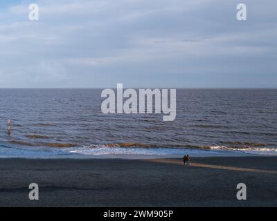 couple on beach standing in the sunlight - Southwold, Suffolk UK Stock Photo