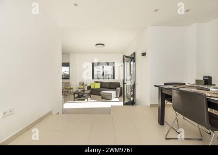 Living room on two levels of a single-family home with smooth white painted walls and metal carpentry of black aluminum and glass windows and doors Stock Photo