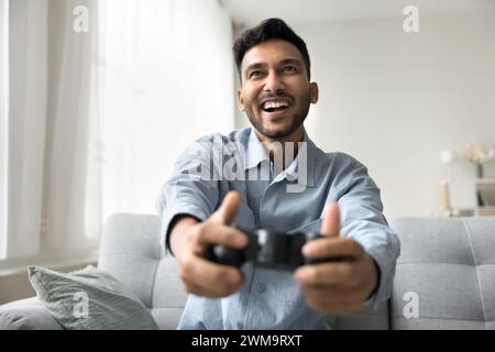 Excited Indian man holding gamepad controller playing video games Stock Photo