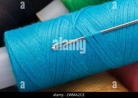 Multi-colored threads on spools and a steel needle. Macro photography, close-up Stock Photo